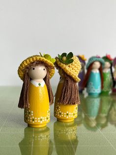 two wooden dolls are standing next to each other on a green surface with white wall in the background