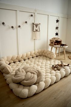 a couch made out of stuffed animals in a room with white walls and wooden floors