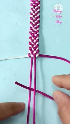 someone is making a piece of yarn with pink and white strips on the end of it