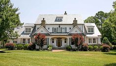 a large white house sitting in the middle of a lush green field next to trees