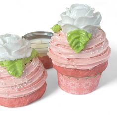 two cupcakes with pink frosting and green leaves