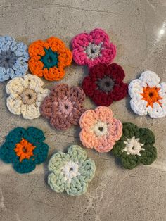 several crocheted flowers sitting on top of a marble counter next to each other