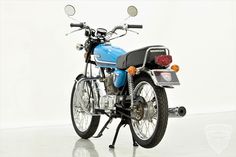 a blue and black motorcycle parked on top of a white floor next to a wall