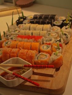 sushi platter with chopsticks and dipping sauce on wooden cutting board in kitchen area