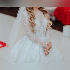 a woman in a white wedding dress with long sleeves and a veil on her head