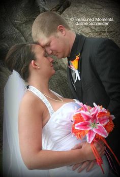 a bride and groom kissing in front of a rock