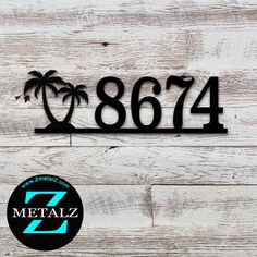 a metal house number sign with two palm trees on the front and back of it