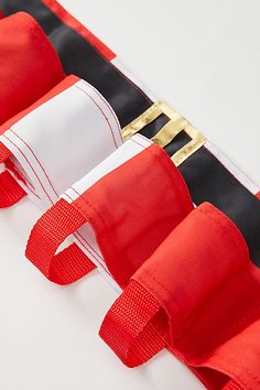 three pieces of red and black material with gold hardware on each side, lined up against one another