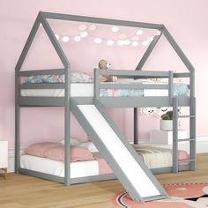 a child's bed with a slide in the middle and a pink wall behind it