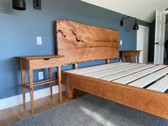 a wooden bed frame in a bedroom with blue walls and wood flooring on the side