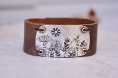 a brown leather bracelet with flowers on it