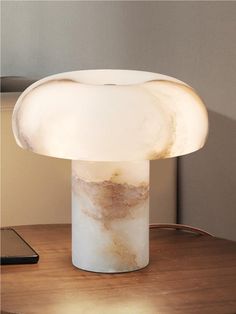 a mushroom lamp sitting on top of a wooden table next to a cell phone and remote control