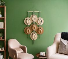 a living room with green walls and hats hanging on the wall above two white chairs