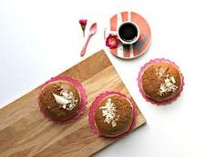 three cupcakes sitting on top of a wooden cutting board next to a cup of coffee