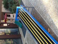 a blue and yellow bench sitting in front of a building