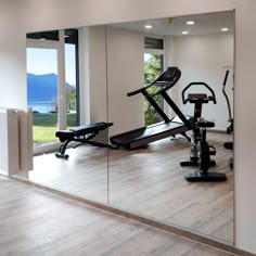 an exercise room with mirrors and treadmills