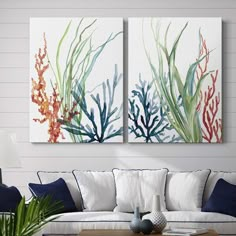 two paintings on the wall above a couch in a room with white walls and blue accents