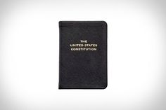 a black book with the words the united states constitution written in gold on it's cover