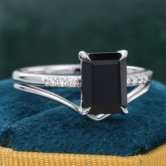 a black diamond ring sitting on top of a blue velvet cushion