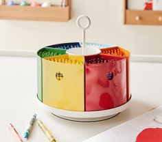 a multicolored container with scissors and pens on a white table next to other items