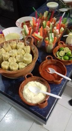 a table topped with bowls filled with different types of food and dipping sauces on skewers