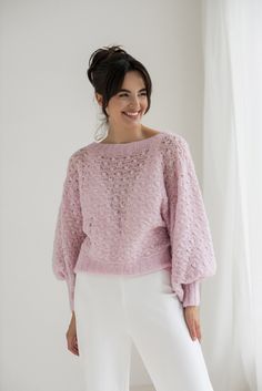 a woman wearing a pink sweater and white pants