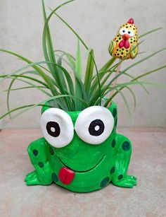 a green frog planter with googly eyes and a red heart on its nose