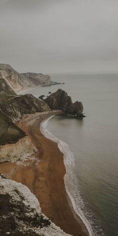 an aerial view of the beach and cliffs on a foggy day in wintertime