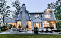 a large gray house sitting on top of a lush green field