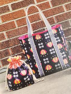 two bags sitting on the ground next to a brick wall with an umbrella print bag