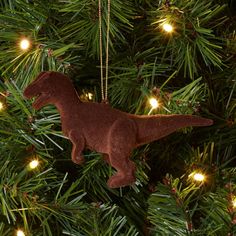 a brown dinosaur ornament hanging from a christmas tree with lights on it's branches