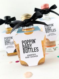 three baby bottles with labels on them sitting next to confetti