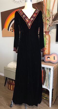 Absolutely gorgeous!  Late 1960's Black Velvet A-Line Maxi Dress by Toni Todd Beautifully made, elegant style 10" Deep V Neckline Trimmed in 2" Wide Multi Color Floral Embroidery Fully Lined in Black Nylon Fabric 15 " Back Zipper MEASUREMENTS (in inches):                                                                                                                    Shoulder to Shoulder from the back 15" Bust : 38" Waist: 34" Hips: 48" Side Length underarm to hem 51" Arm Length underarm to cuff 16" 2" Embroidery Design Cuff Neck Opening:  Front V Back of Neck to Hem 51" front - 50" Skirt Circumference 92" INTERNATIONAL CUSTOMER?? Please email for Shipping Info Traditional Formal Dress For Fall, Traditional Fall Party Dresses, Vintage Embroidered Costume Dress, Vintage Embroidered Fall Dresses, Vintage Fall Costume Dresses, Retro Long Sleeve Vintage Dress For Costume, Vintage Dress For Fall Costume, Retro Long Sleeve Vintage Costume Dress, Vintage Costume Dress For Fall