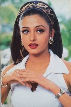 an old photo of a woman wearing a white shirt and leopard print headband with her hands on her chest