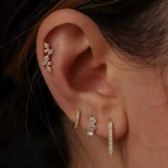 a woman's ear with three small stars on the top and two smaller ones on the bottom