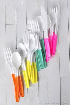 there are many different colored plastic spoons on the table