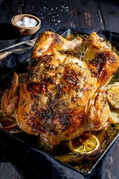 a roasted chicken on a tray with garlic and lemons