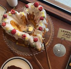 a cake with white frosting and raspberries is on a glass platter