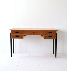 a wooden desk with two drawers on it's sides, against a white wall