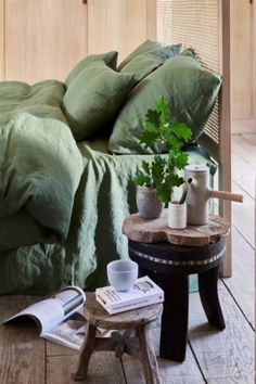 a bed sitting on top of a wooden floor next to a table with a potted plant