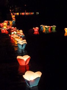 paper lanterns floating in the water at night