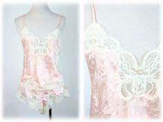 Vintage 1980s camisole and tap pants set. Pale pink, silky polyester has a shadow print. Trimmed with cream lace. Top has spaghetti straps. Tap pants have elastic waist meant to be worn at the waist with high cut legs. Label reads, "Lucie Ann II, made in the USA." Pants are marked size small and I believe the cami is size 34 (the label is a bit worn). Freshly laundered. Excellent condition.  Measurements: Camisole Bust = 34" Waist = 34" Length from top of shoulder to hem = 20" Pants Waist = 18" - 28" Hips = 40" Length from waist to middle of crotch = 13.5" All measurements are taken with the garment flat, doubled for the bust (chest), waist, hips, and circumference. Please make sure you leave yourself a little wiggle room for a comfortable fit! Some garments may be clipped to show proper f Pink Spaghetti Strap Camisole For Pajama Party, Pink Camisole For Pajama Party, Pink Fitted Camisole For Pajama Party, Fitted Pink Camisole For Pajama Party, Pink Lace Camisole In Coquette Style, Pink Lace Trim Camisole For Pajama Party, Pink Lace Coquette Camisole, Pink Satin Camisole, Pink Lace Trim Camisole In Coquette Style