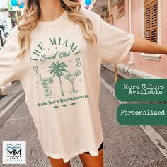 "Are you heading out on a Miami bachelorette trip and need some cute beach tees?  These personalizable bachelorette tees are perfect for all of your group.  Featuring cocktails and \"The Miami Club\", along with your name and destination.    These vintage style tees can be sized up for an oversized baggie look to wear on the beach or after the pool.    Available in Comfort Colors ™ T-Shirts in six beautiful colors.    Check my store for matching sweatshirts.   Product Quality *  Comfort Colors© t-shirts are made of 100% ultra-soft ringspun cotton featuring a relaxed fit and vintage look.    For a trendy oversized look, order 1 to 2 sizes up from your normal size.   They are a little thicker than other t-shirts and have a vintage feel and look to them.   This design features a vintage overl Summer Crew Neck T-shirt For Bachelorette Party, Casual T-shirt For Bachelorette Party In Summer, Casual Summer T-shirt For Bachelorette Party, Casual Short Sleeve T-shirt For Bachelorette Party, Summer Bachelorette Party T-shirt With Letter Print, White T-shirt For Bachelorette Party In Summer, Summer Honeymoon T-shirt With Short Sleeves, Summer Honeymoon Short Sleeve T-shirt, Short Sleeve T-shirt For Summer Honeymoon