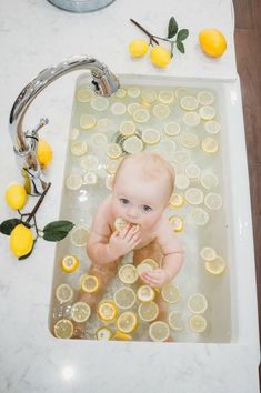 a baby sitting in a bathtub with lemons around it