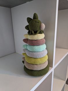 a stack of crocheted pillows sitting on top of a white book shelf in a room