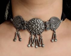 Add charm and charisma to your beautiful personality with these stunningly handcrafted choker set in antique silver look Earrings are also designed beautifully and compliment the choker very well. Wear it with any of your formal or casual outfits and grab compliments all the way! Length of the metal part in the choker is 4 inches approx with a 10 inch adjustable black chord (dori at the back) Weight of the choker 42gms Each earring weighs 10 GM's Length 1.5 inches Note: All in stock items will b Metal Choker With Oxidized Finish In Temple Jewelry Style, Oxidized Metal Temple Jewelry Choker, Traditional Metal Choker For Festivals, Bohemian Tilla Choker Jewelry, Oxidized Temple Jewelry Style Choker, Silver Choker For Festivals, Temple Jewelry Style Oxidized Choker, Oxidized Temple Jewelry Choker, Festive Oxidized Finish Choker For Festivals