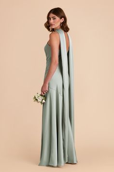 a woman in a long green dress with an open back, holding a flower bouquet