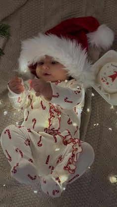 a baby wearing a santa hat laying on top of a bed