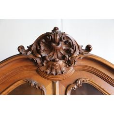 an ornate carved wooden door with mirror on the top and bottom panel, in front of a white wall