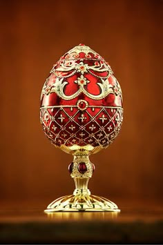 an ornately decorated red and gold egg on a stand